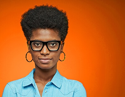 Uma mulher negra de óculos em um fundo laranja.