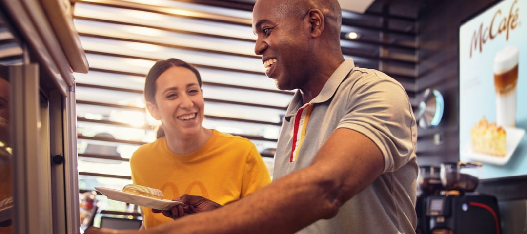 Two McDonalds employees smiling while working 